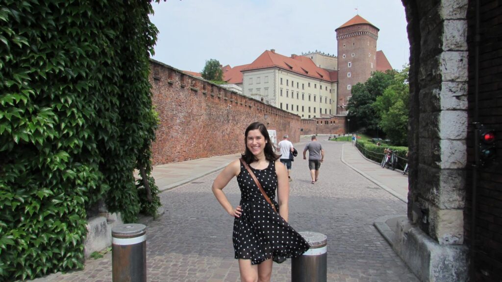 kate storm standing at the entrance gate to wawel castle grounds, one of the best things to do in krakow itinerary