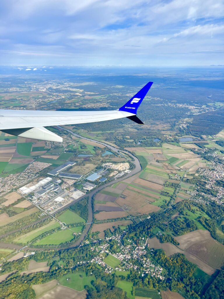 plane wing in the foreground of the photo with french countryside visible below