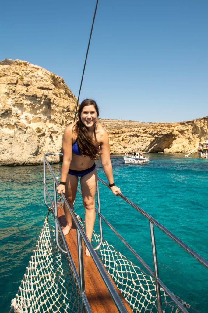 Things to Do in Malta: kate storm on the bow of a boat in Crystal Lagoon