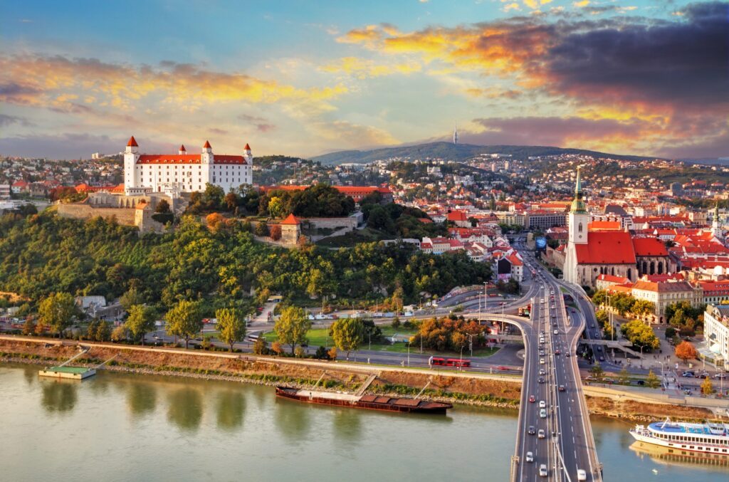 aerial view of bratislava at sunset with castle visible to the left of the photo and danube in the foreground