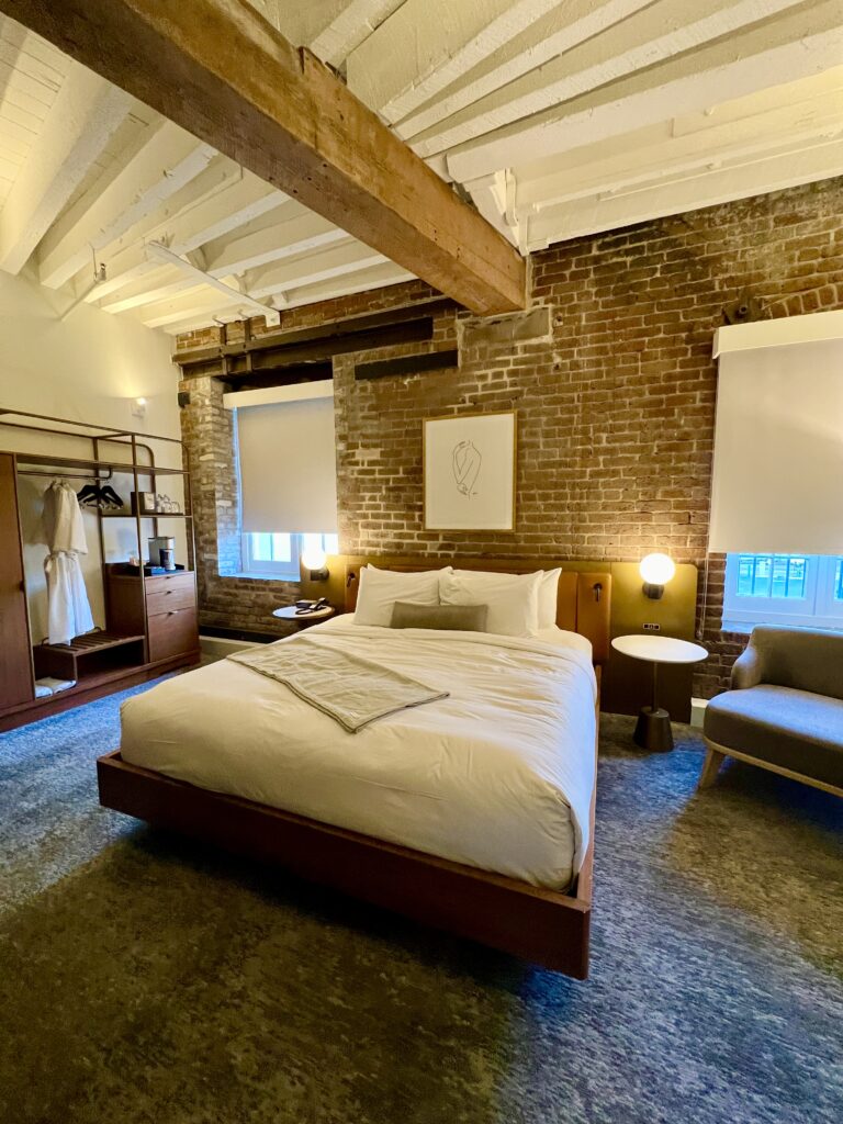 bed in a modern room with dramatic ceiling beams in the one11 hotel new orleans