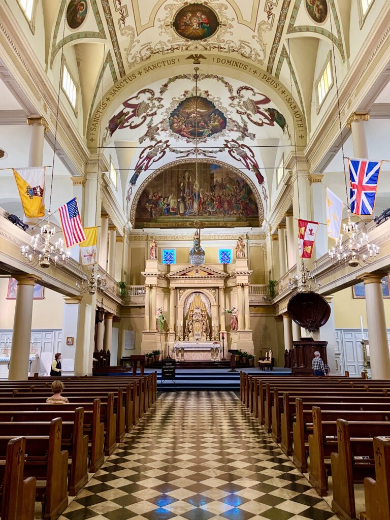 interior of st louis cathedral in new orleans with checkered tile and colorful flags inside