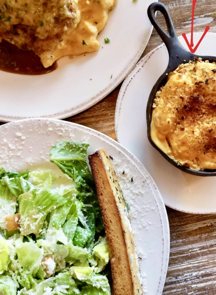 food spread of a salad, chicken parmesan, and smoked gouda mac and cheese from red dog diner restaurant new orleans