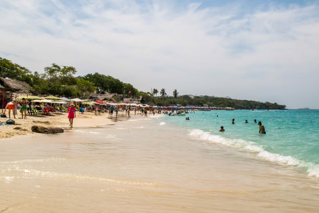 playa blanca cartagena as seen from the shore, looking down the beach toward huts and patrons