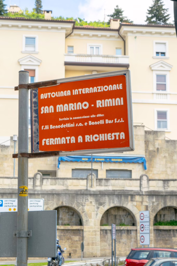 red sign displaying the bus stop for riding between rimini and san marino by bus