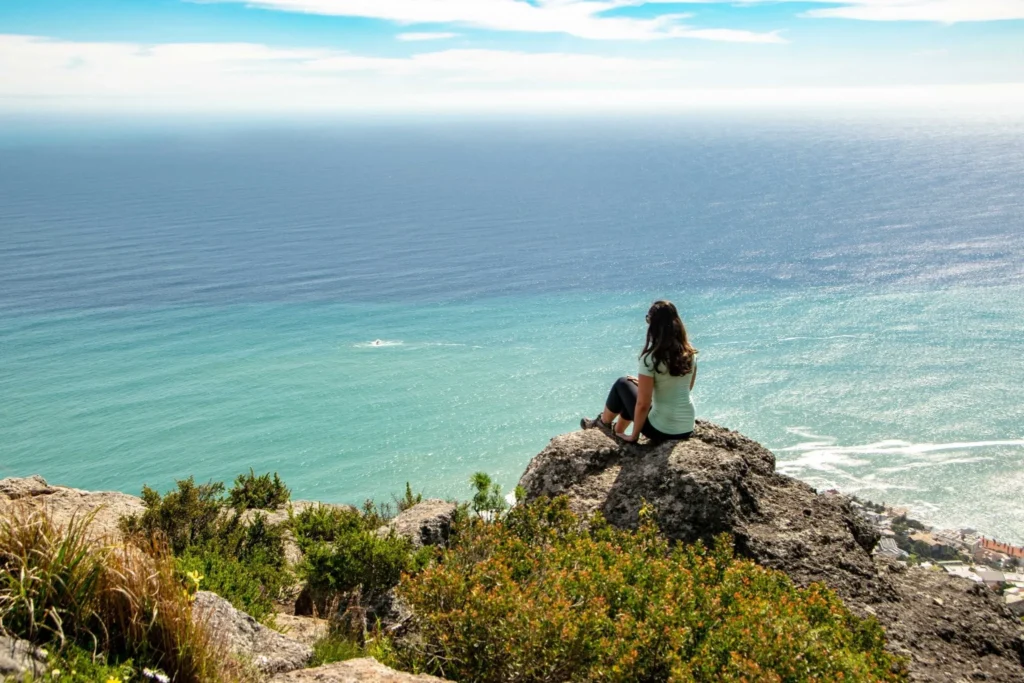 kate storm overlooking ocean when hiking lions head as part of a cape town itinerary