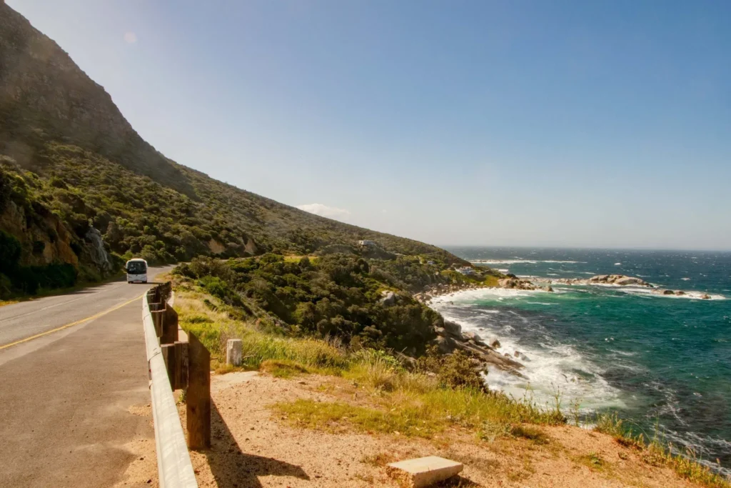 coastal road near cape peninsula in south africa with a bus driving up the road on the left and the ocean on the right, a beautiful sight during 2 weeks in south africa