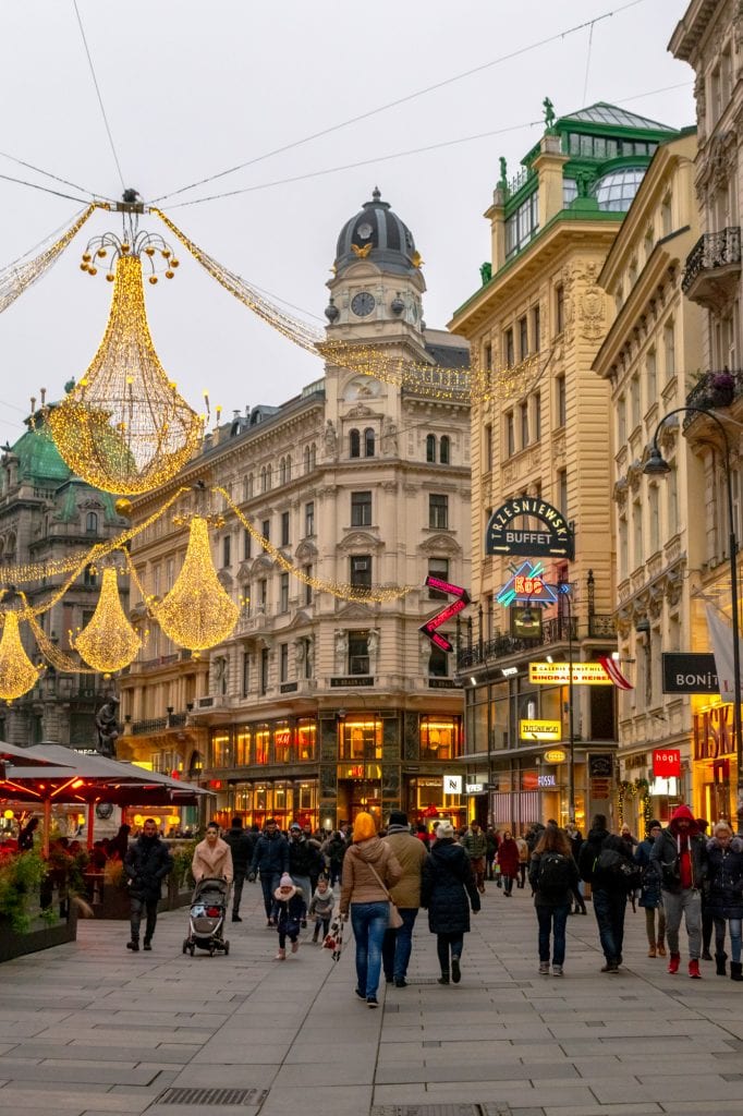 bustling street in vienna austria with large lanterns hung above it to decorate for christmas