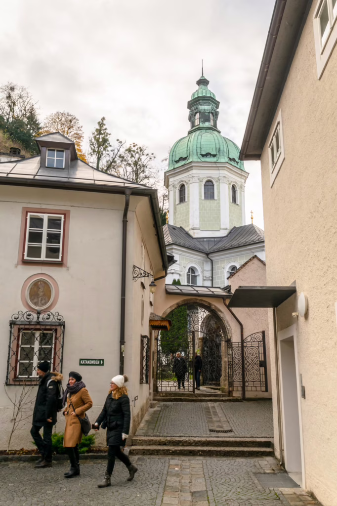 travelers exploring the streets of salzburg austria in december, with green-domed building visible behind them