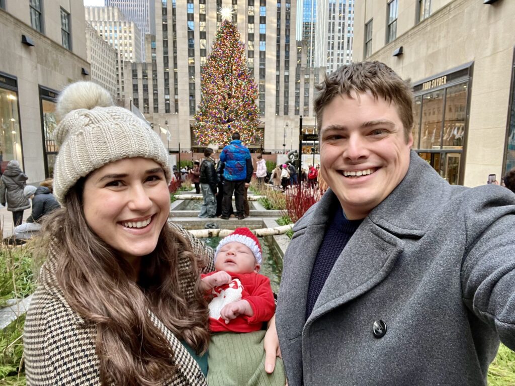 kate storm jeremy storm and their baby taking a selfie in front of the rockefeller christmas tree in new york city