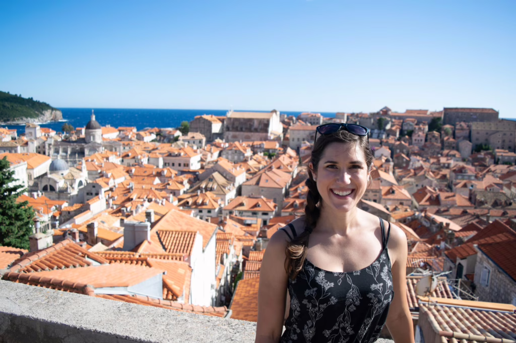 kate storm standing on the dubrovnik city walls wearing a black dress in july