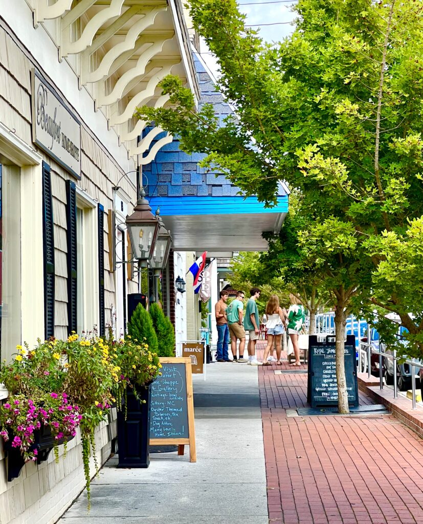 sidewalk in beaufort north carolina with window boxes visible to the left and the entrance to royal james cafe in the distance