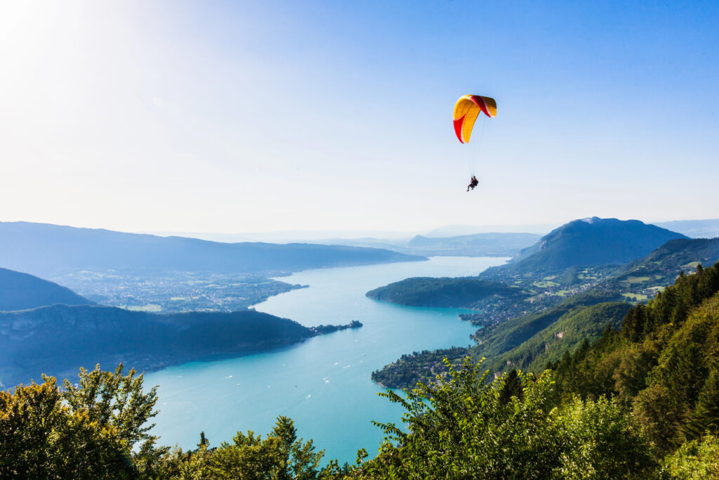 paraglider over lake annecy in the french alps on a sunny summer day