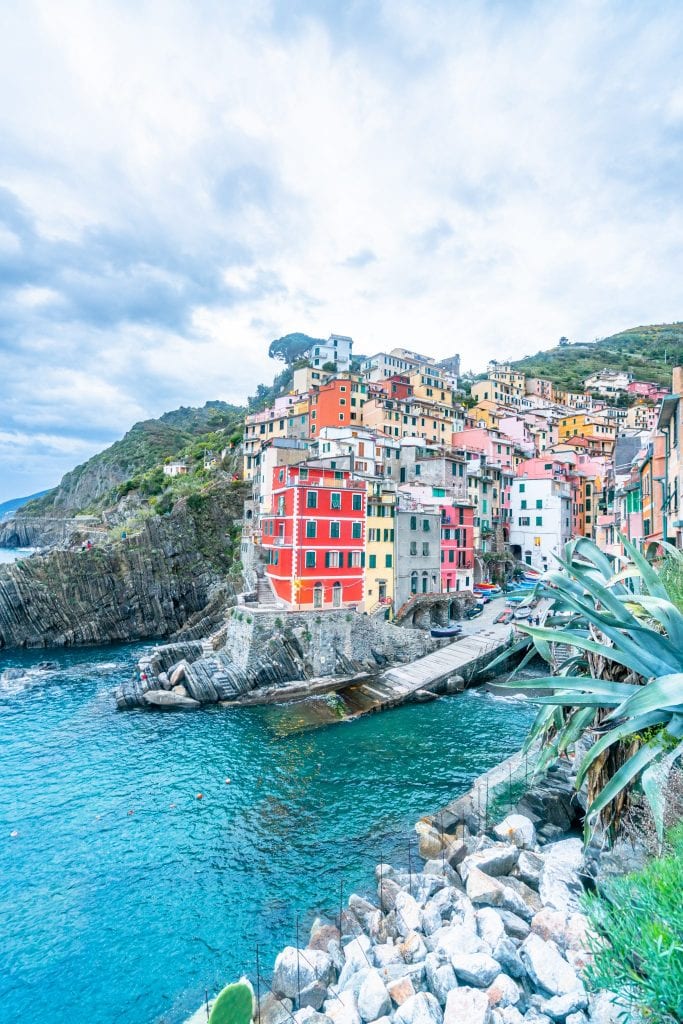 view of riomaggiore harbor on a cloudy afternoon as seen from hiking trail