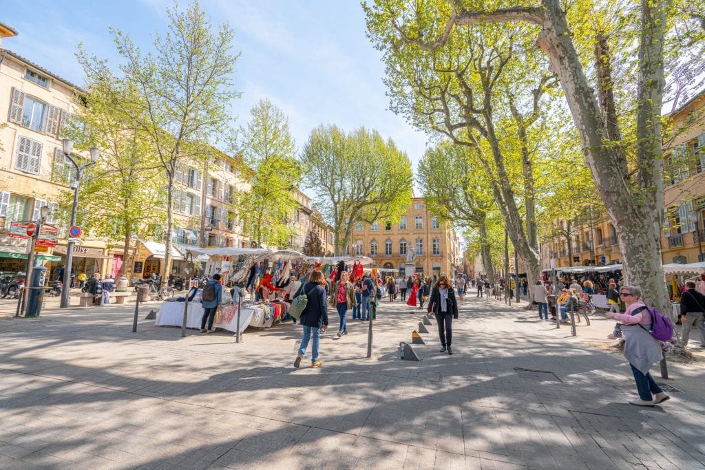 market in a shady square of aix en provence france with shoppers in the center