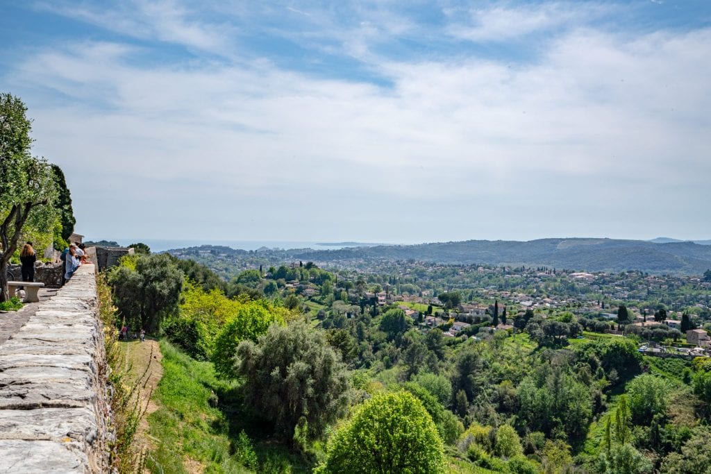 view of cote d'azur and countryside from saint-paul-de-vence city walls, stone walls visible to left of the photo and mediterranean sea visible in the distance