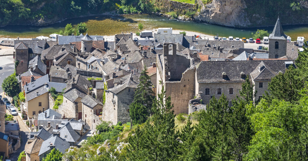 Sainte-Enimie france as seen from above with stone buildings in the foreground and river in the background