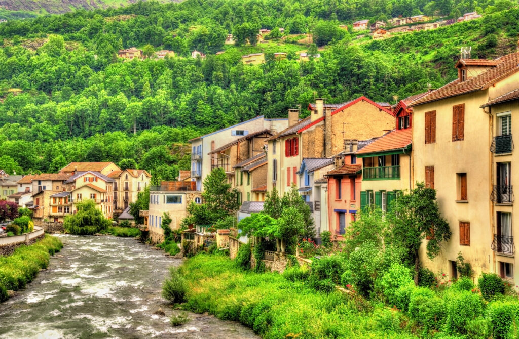 colorful buildings along a lush river in ax-les-thermes midi-pyrenees france