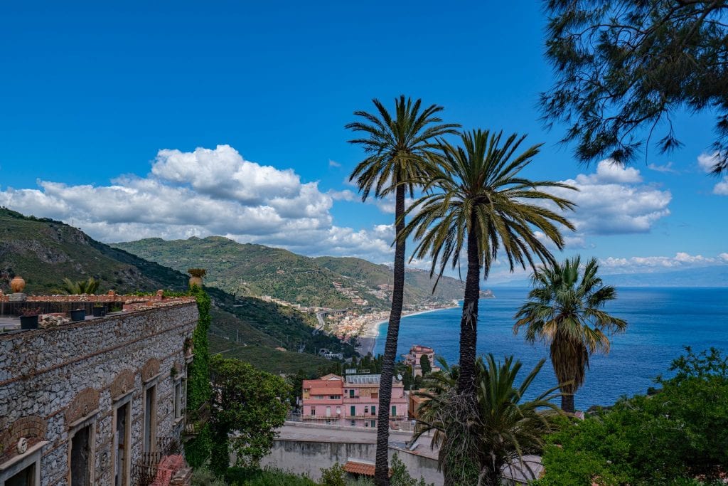 view of ionian sea from taormina sicily with palm trees in the foreground