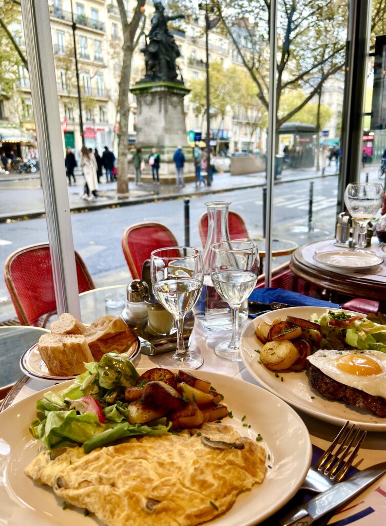 omelet and other food on a table in front of a window in a paris brasserie