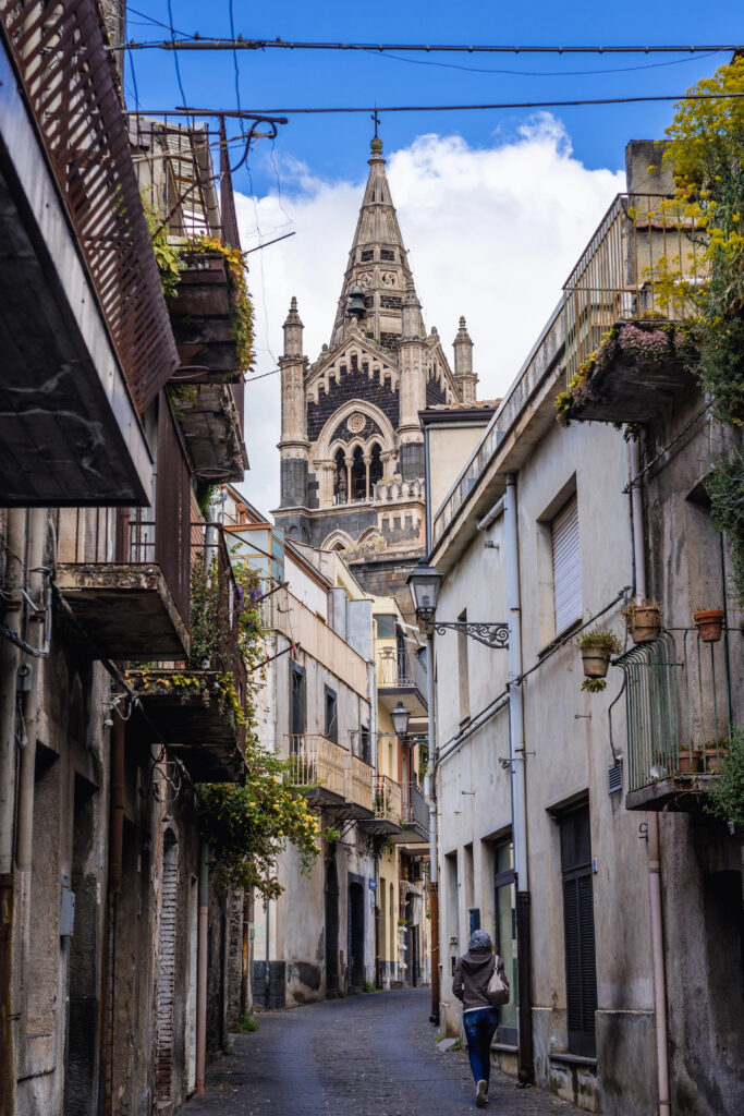 view of a small street in randazzo sicily lined with buildings and the tower of the basilica visible at the end of the street