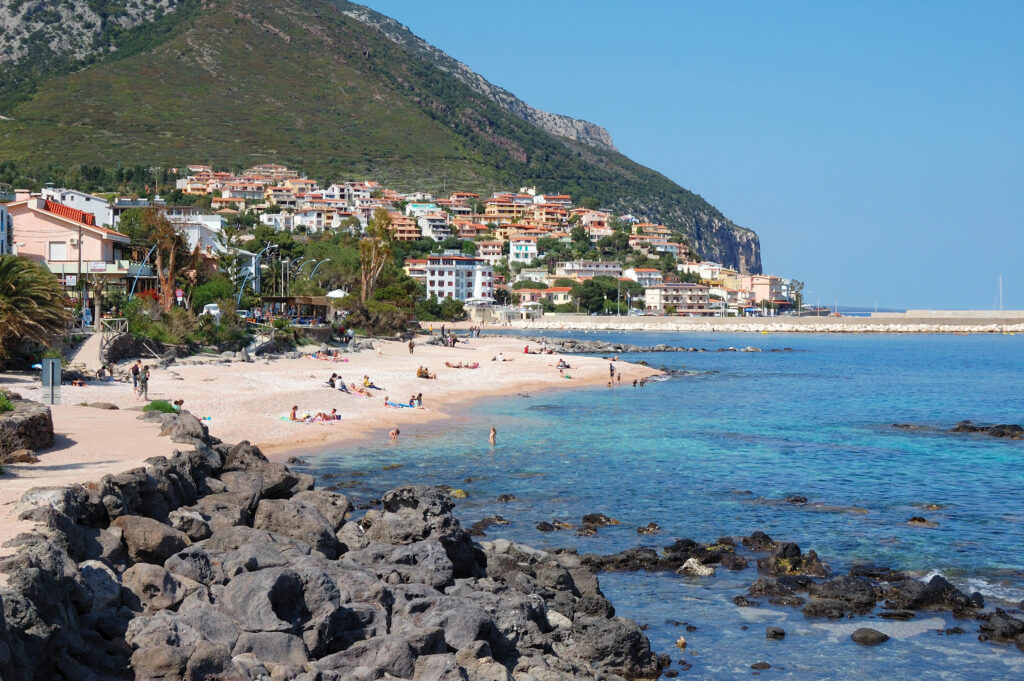 view of cala gonone sardinia italy from rocks outside of town with water and beach in the foreground
