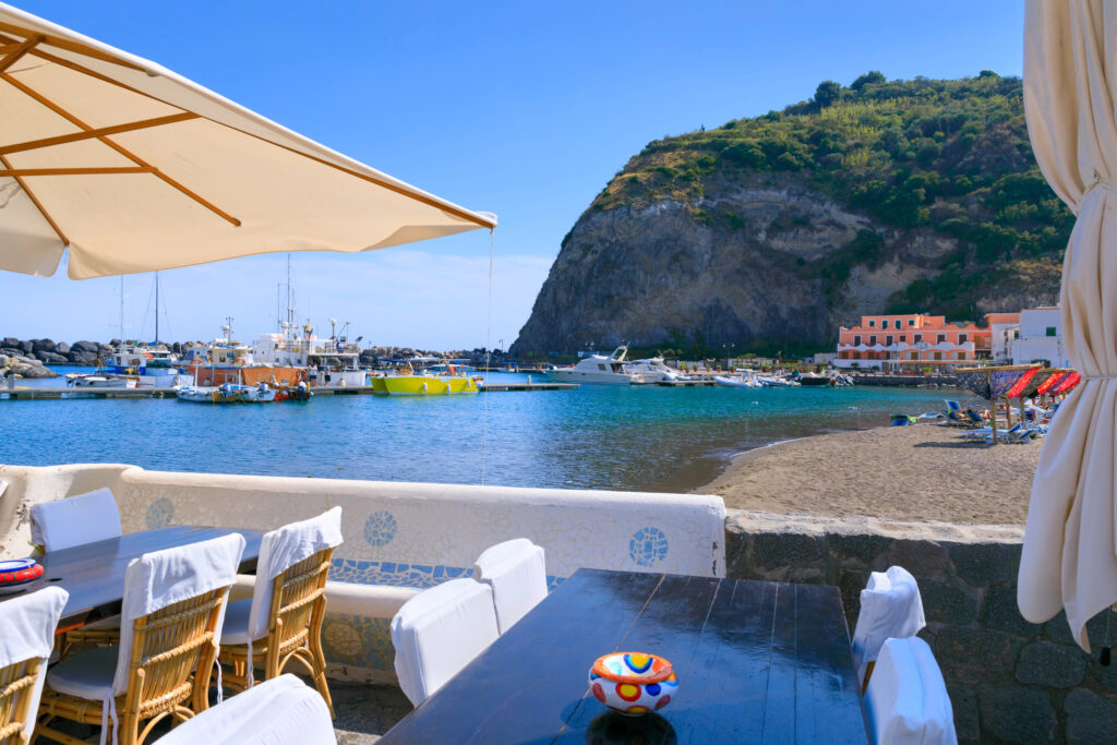 view of sant'angelo town in ischia italy, with restaurant in the foreground and beach in the background