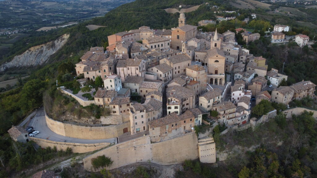 view of Montedinove in le marche italy as seen from above, showing oval shaped village surrounded by town walls