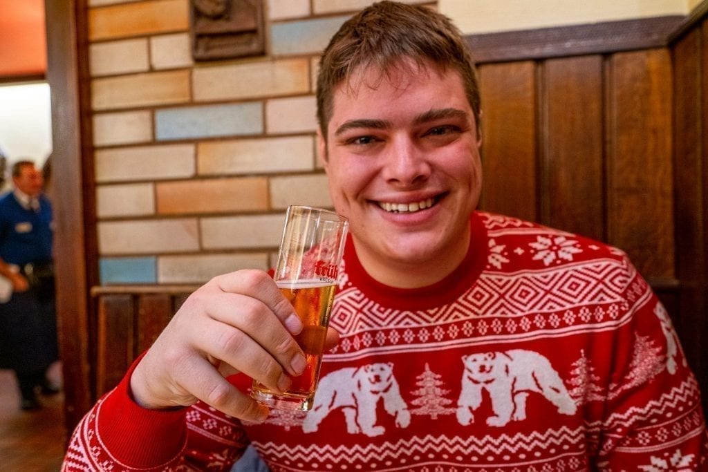 jeremy storm in a red sweater holding up a small Kölsch beer when visiting cologne germany