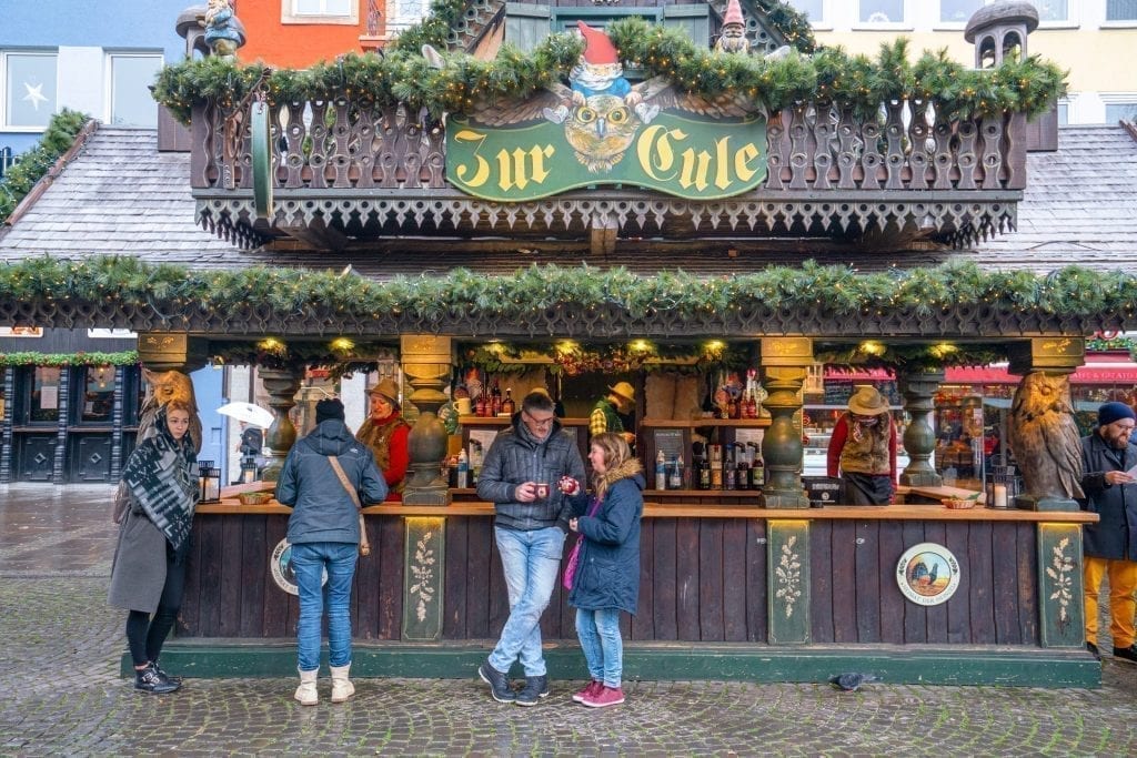 a few people relaxing at a christmas market stand in cologne germany, an amazing destination for a christmas in europe itinerary