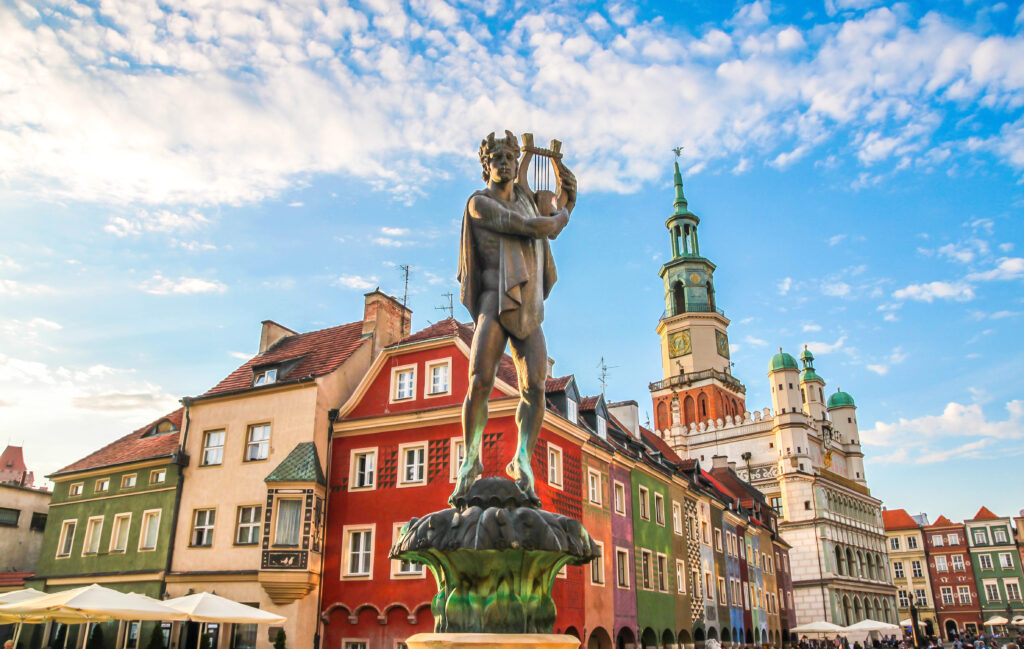 statue of apollo surrounded by colorful buildings on a sunny day in poznan poland, one of the best hidden places in europe to visit