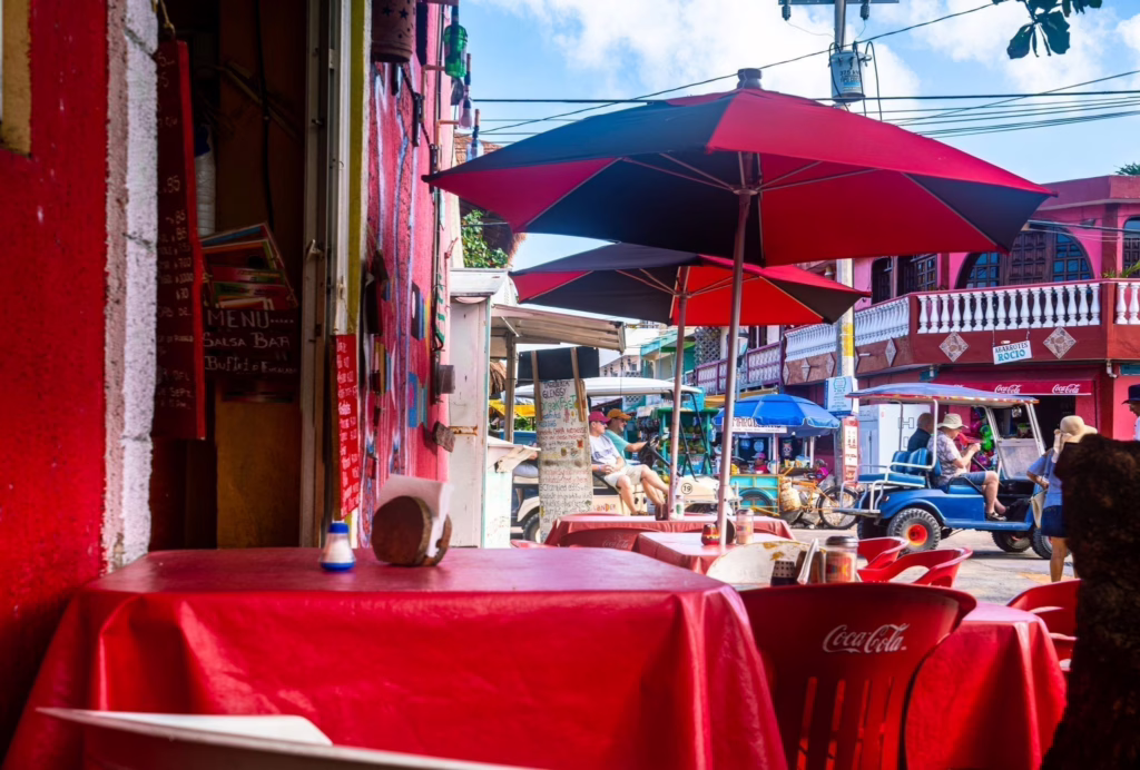 Outdoor restaurant in Mexico with red tablecloths and red umbrellas shading the tables