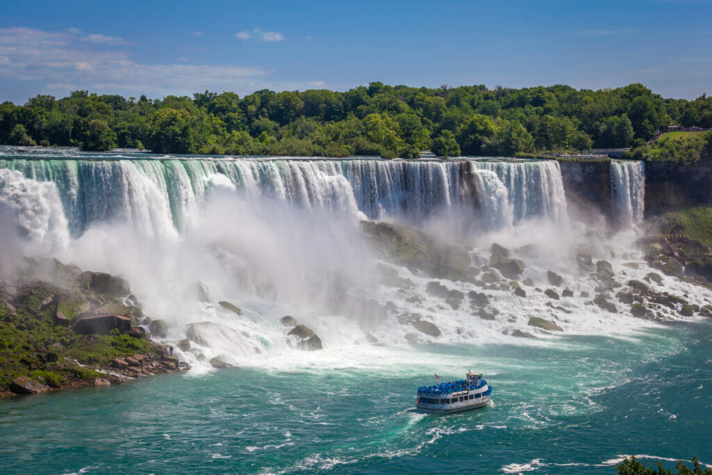 view of niagara falls with maid of the mist tourist boat visible on the water in the foreground