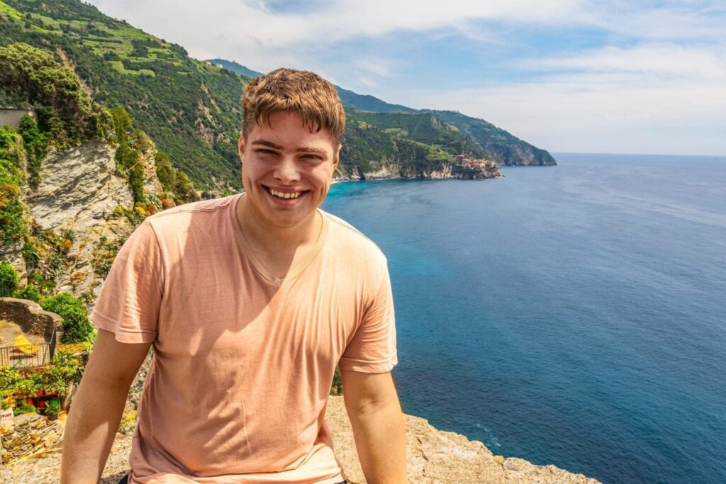 jeremy storm sitting on a ledge overlooking cinque terre from the village of corniglia italy