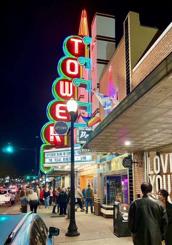 tower theatre facade of oklahoma city lit up on a winter night with red letters and green detail, as seen from the street