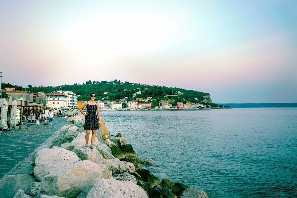 kate storm standing near the water in piran slovenia close to sunset