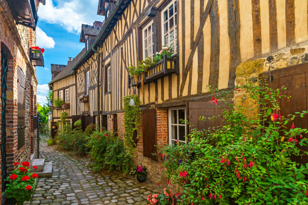 cobblestone street surrounded by yellow half timbered houses in honfleur normandy, one of the most beautiful villages in france