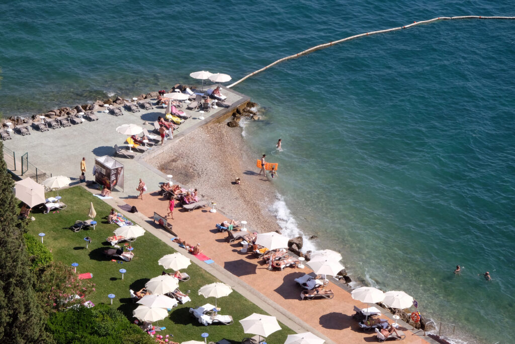 portoroz beach in slovenia as seen from above, with white umbrellas along the shore