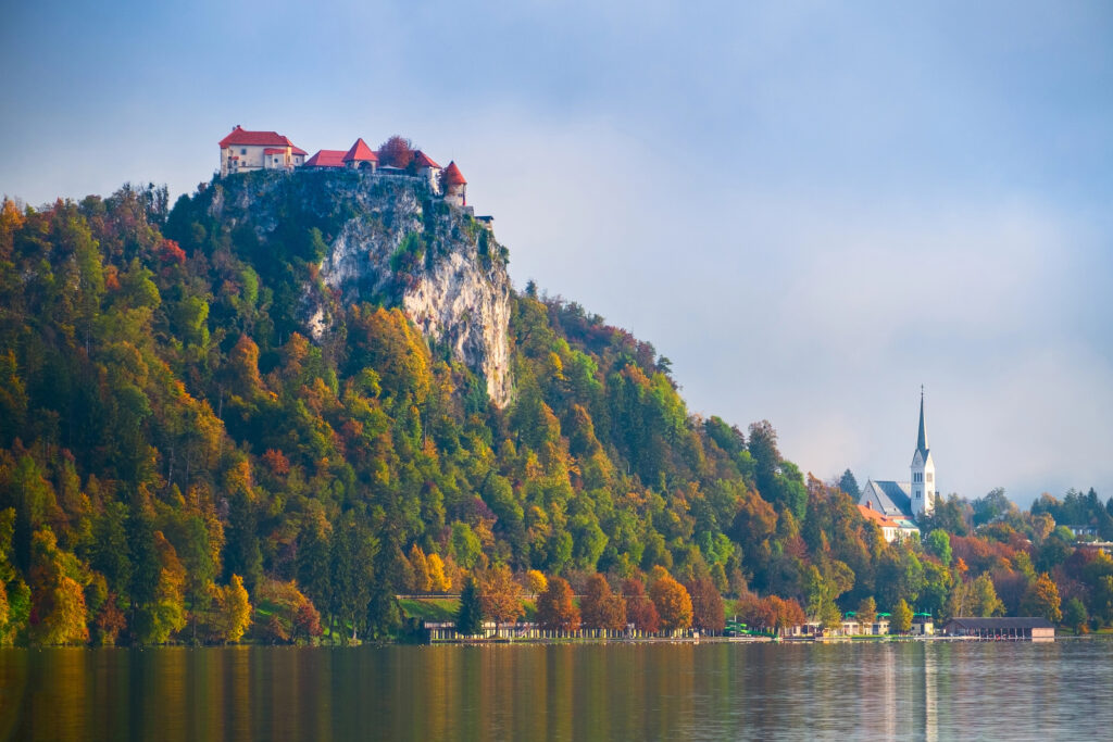 view of lake bled slovenia in the fall, with bled castle perched above the lake