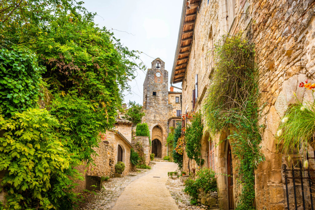 cobblestone street lined with stone buildings and green vines in brunqiuel, a beautiful french village to visit