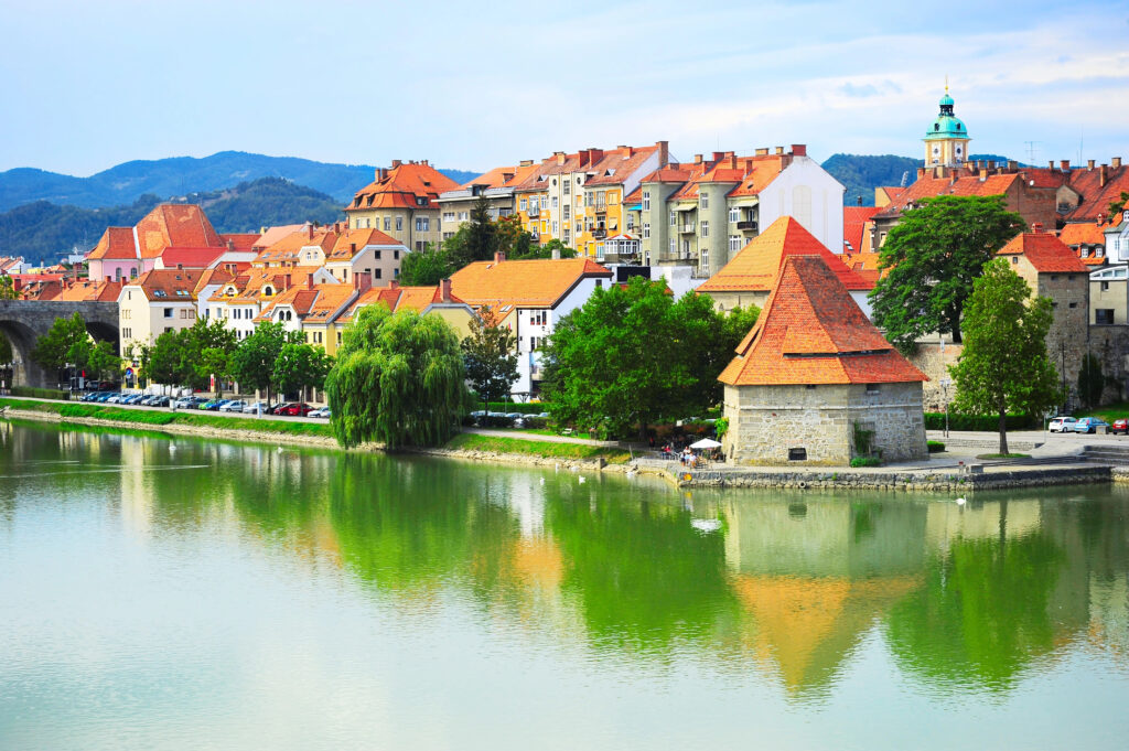 cityscape of maribor slovenia as seen from across the river drava, with river in the foreground