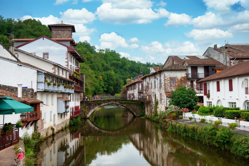 river with a small stone footbridge crossing it in saint jean pied de port, lined with buildings on either side. the start of pilgrimage routes and one of the best places to visit in france