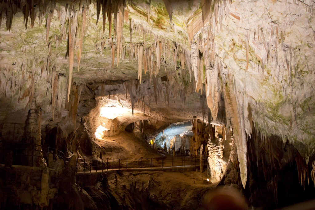 interior of postojna cave, one of the best destinations in slovenia. a walkway for visitors is visible in the center of the photo