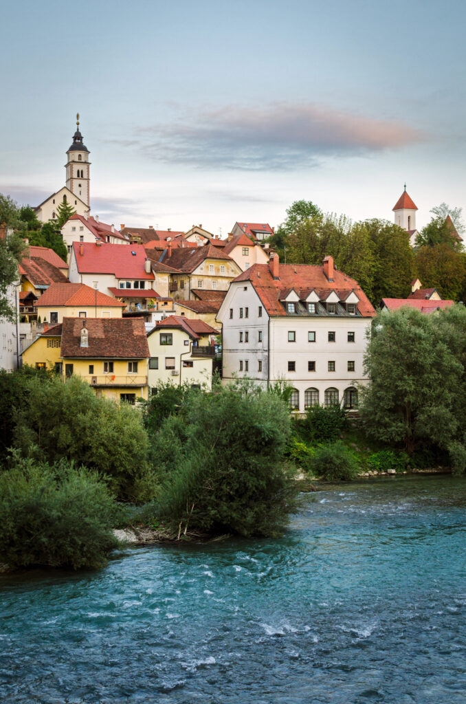 cityscape of kranj slovenia as seen from across the river, with water in the foreground. one of the easiest day trips from ljubljana