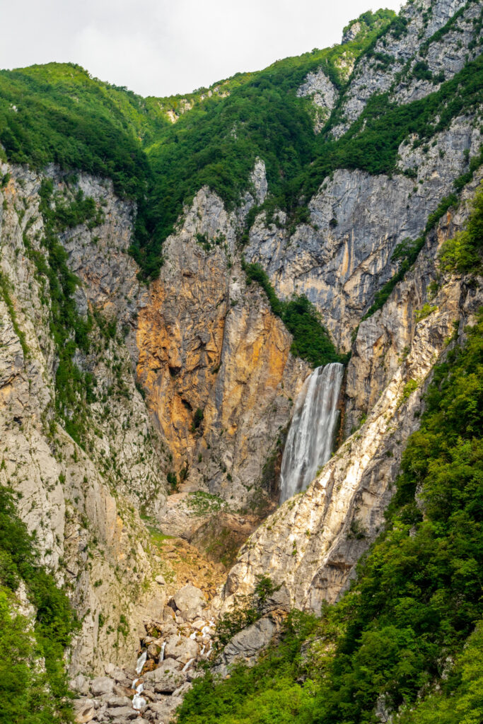 boka waterfall in slovenia falling between a canyon, as seen from afar. one of the most beautiful places in slovenia to visit