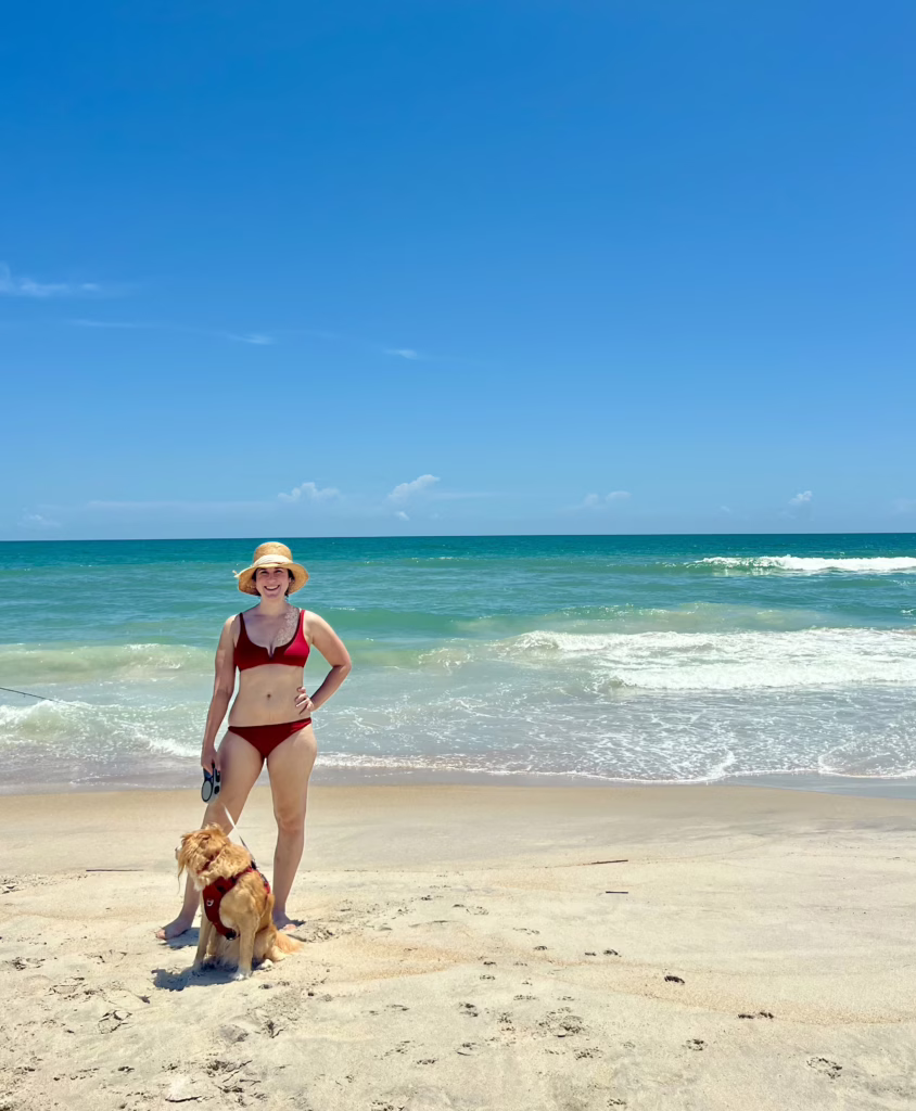 kate storm and her yellow dog ranger standing near the ocean on topsail island north carolina beach on a sunny summer day