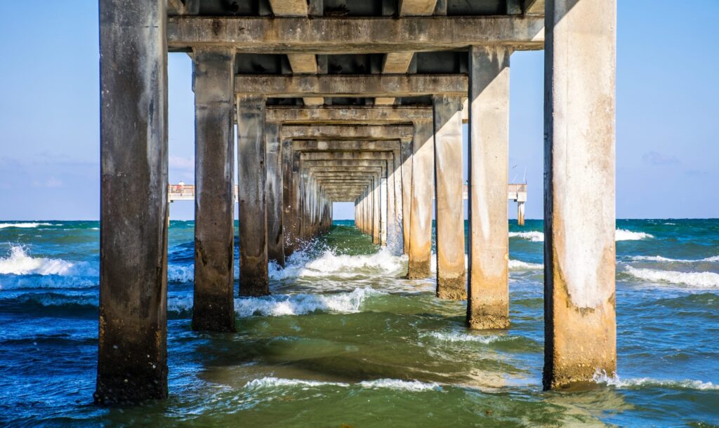 view of the gulf crashing against the shore under a pier in mustang island texas