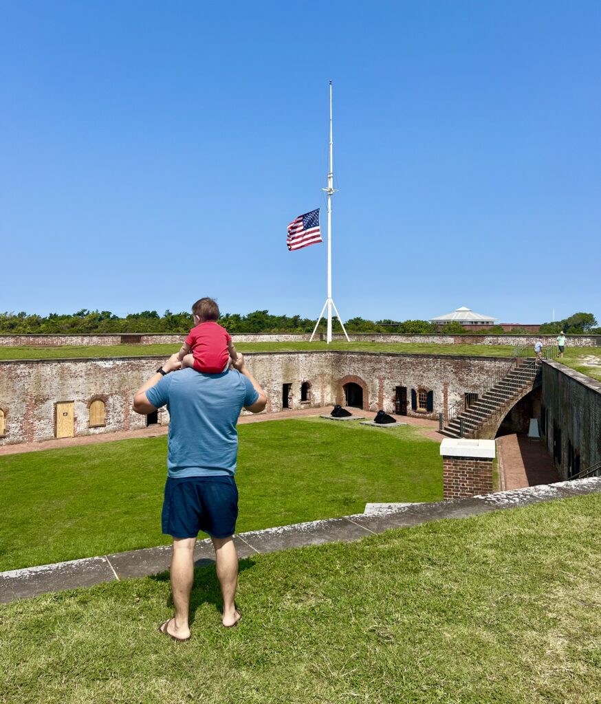 jeremy storm and his baby overlooking fort macon north carolina with american flag in the background