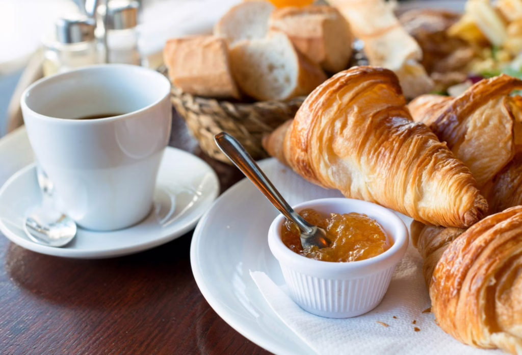 Breakfast in France served on white dishes with coffee, croissants, jam, and butter
