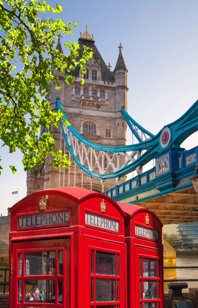 two red british telephone boxes shown in front of tower bridge in london england